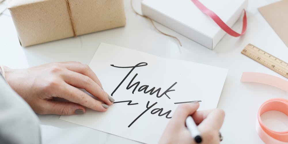 Woman's hand writing thank you note.