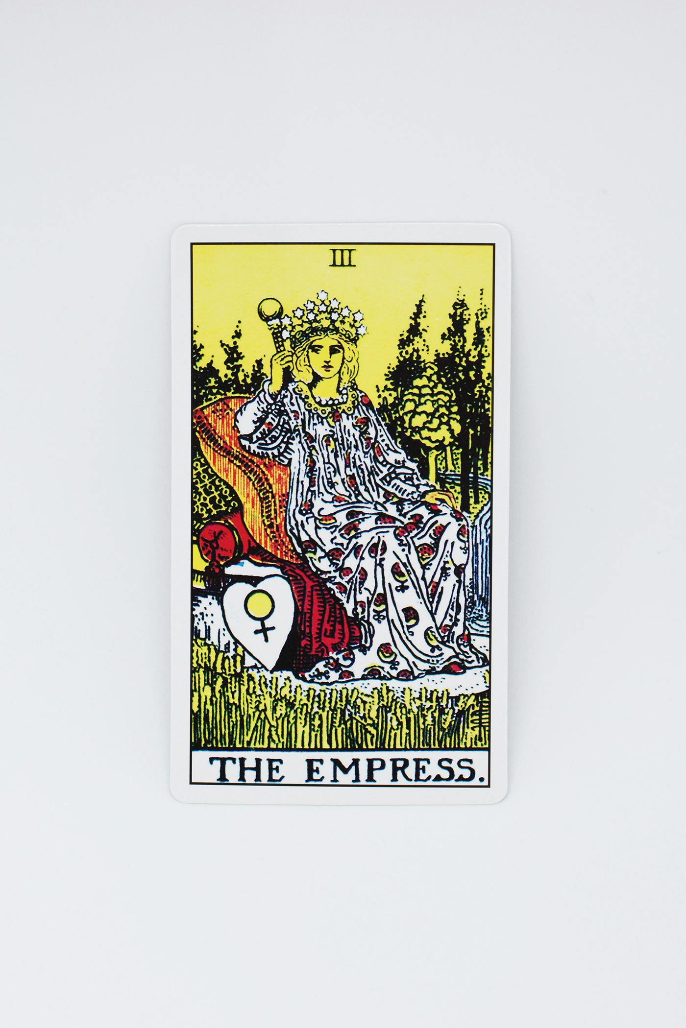 The empress tarot card. Features a women sitting on a throne wearing a crown and holding a crystal wand.
