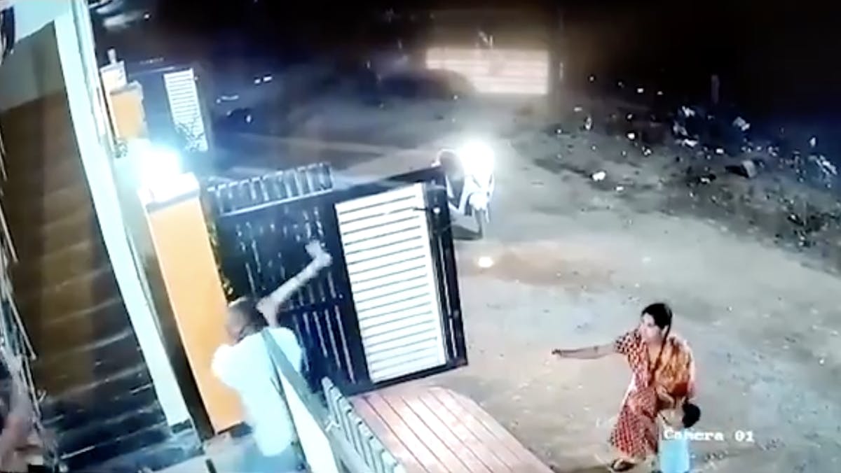 A woman looks on helplessly as a man tries to attack another woman with an ax