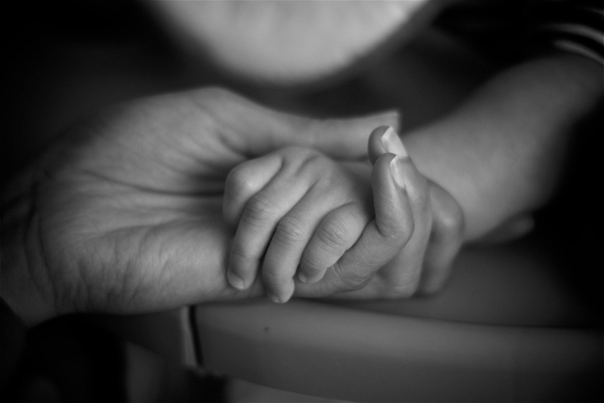 A hand of a parent holding the hand of an infant
