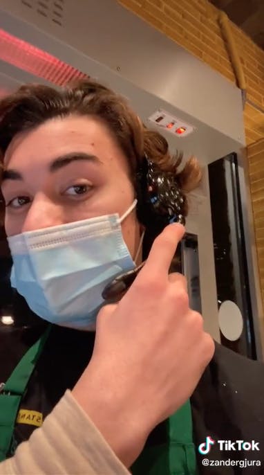 A starbucks employee points to their headset