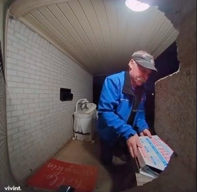 pizza delivery man at customer's front porch dropping box of pizza