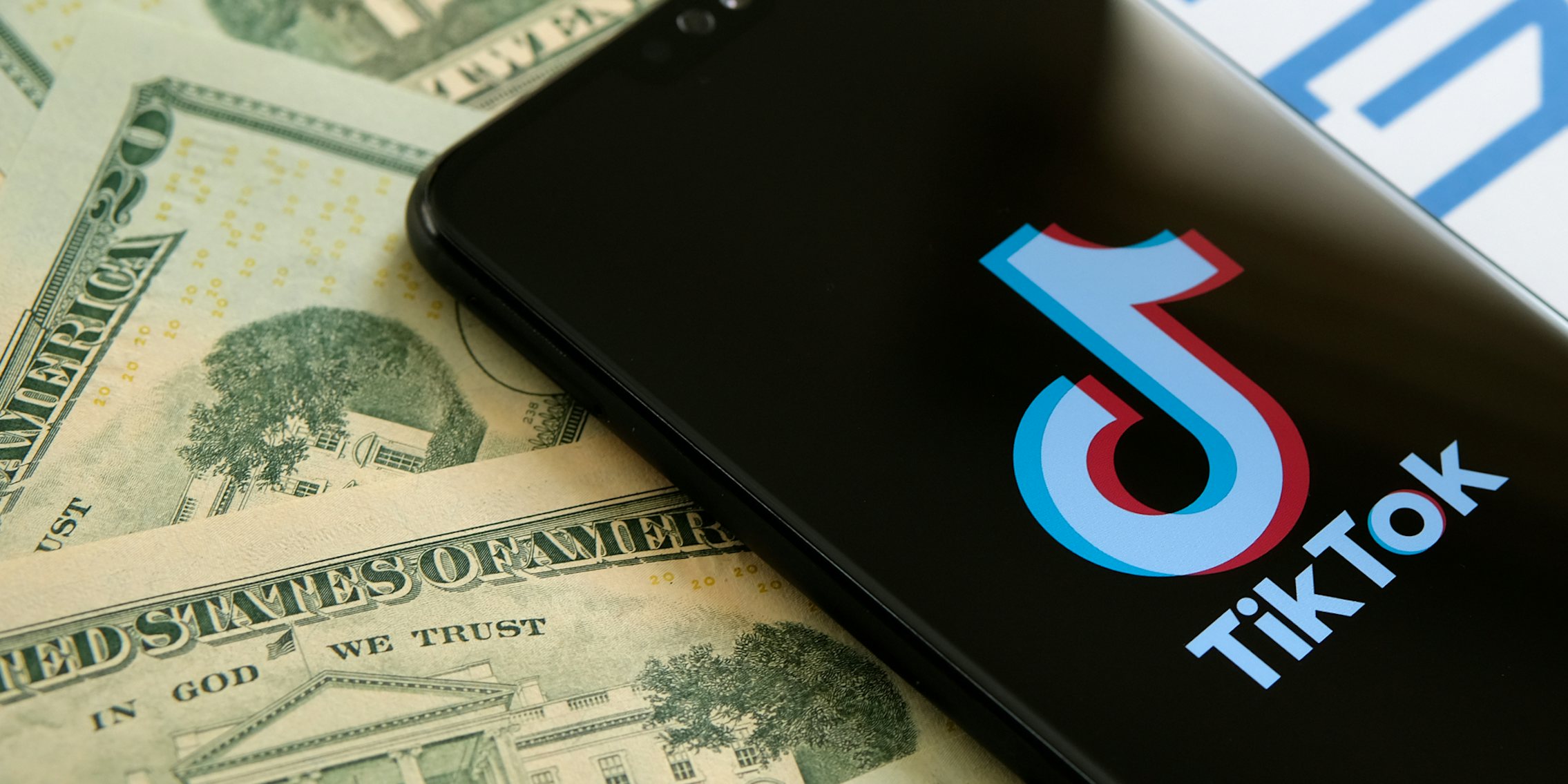 A phone showing the TikTok logo next to $20 bills.