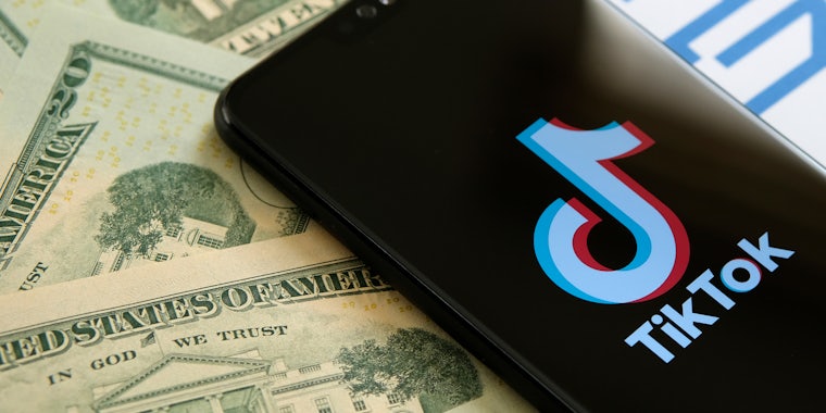 A phone showing the TikTok logo next to $20 bills.