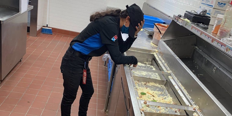 domino's worker leaning over counter with hand on head