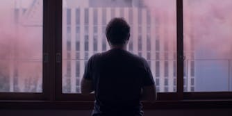 man stares at the window with pink hue
