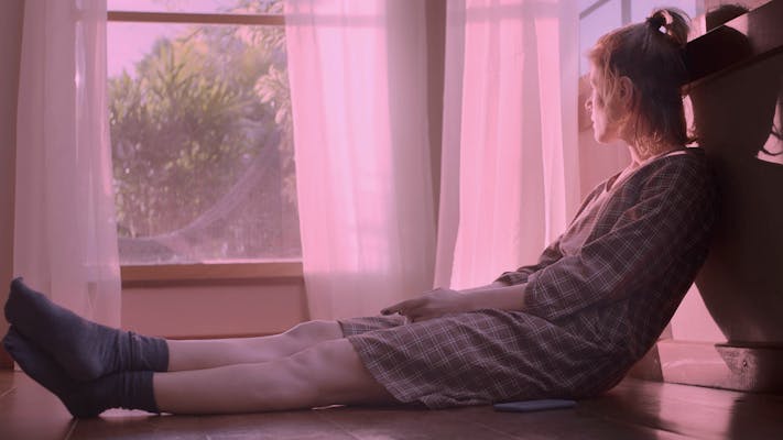 woman stares at the window with pink hue