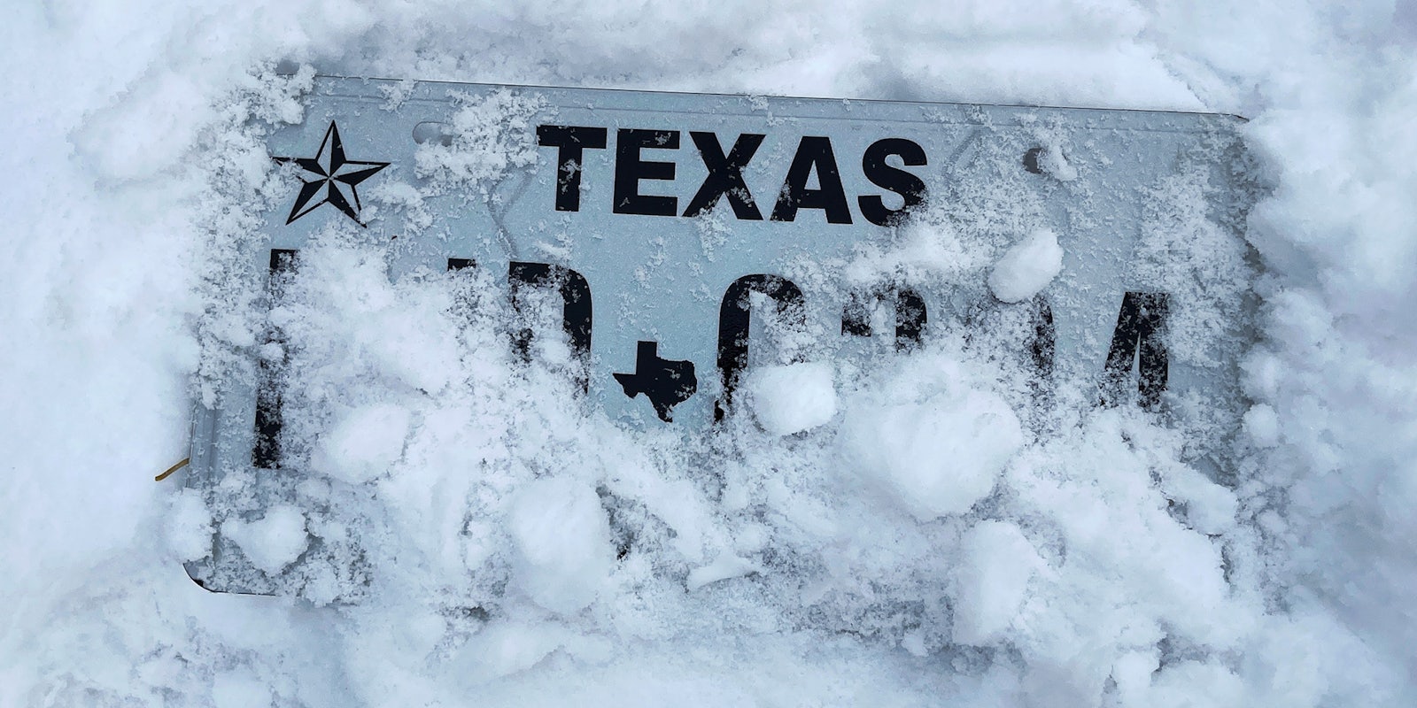 Texas license plate covered in snow