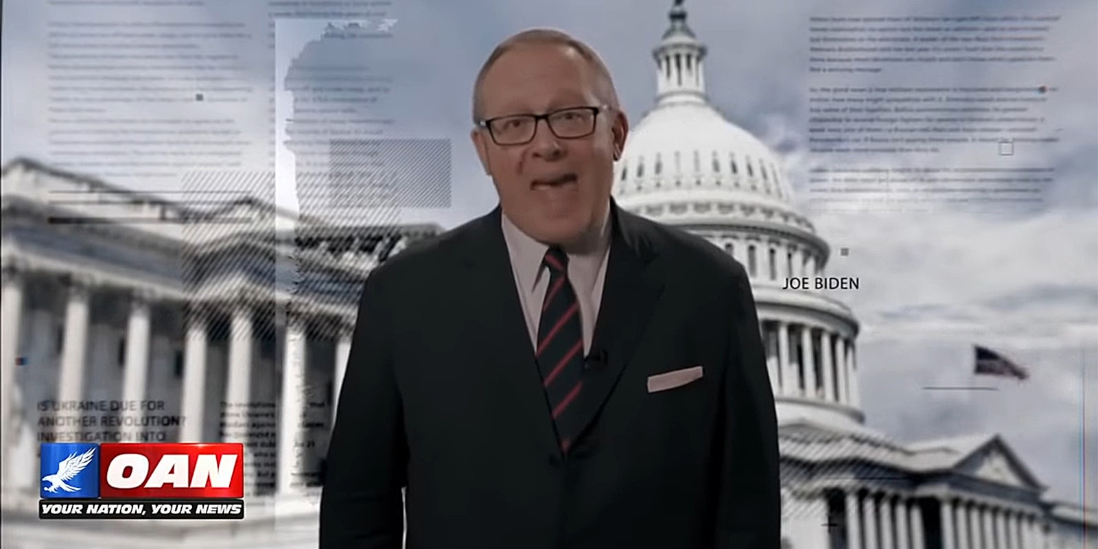 Man speaking in front of US Capitol backdrop with OAN logo