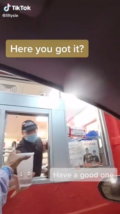 fast food worker handing drink to customer