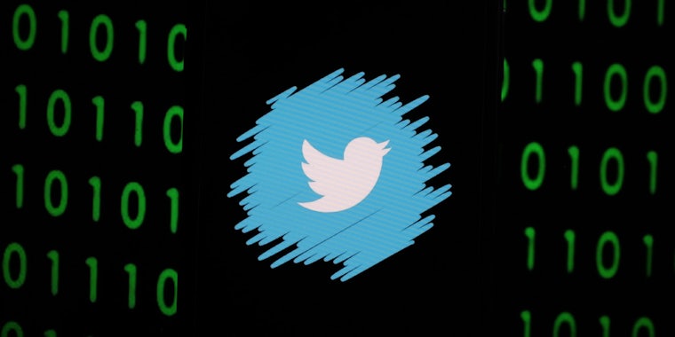 A darkened phone showing the logo of Twitter with a binary 0 and 1 background.