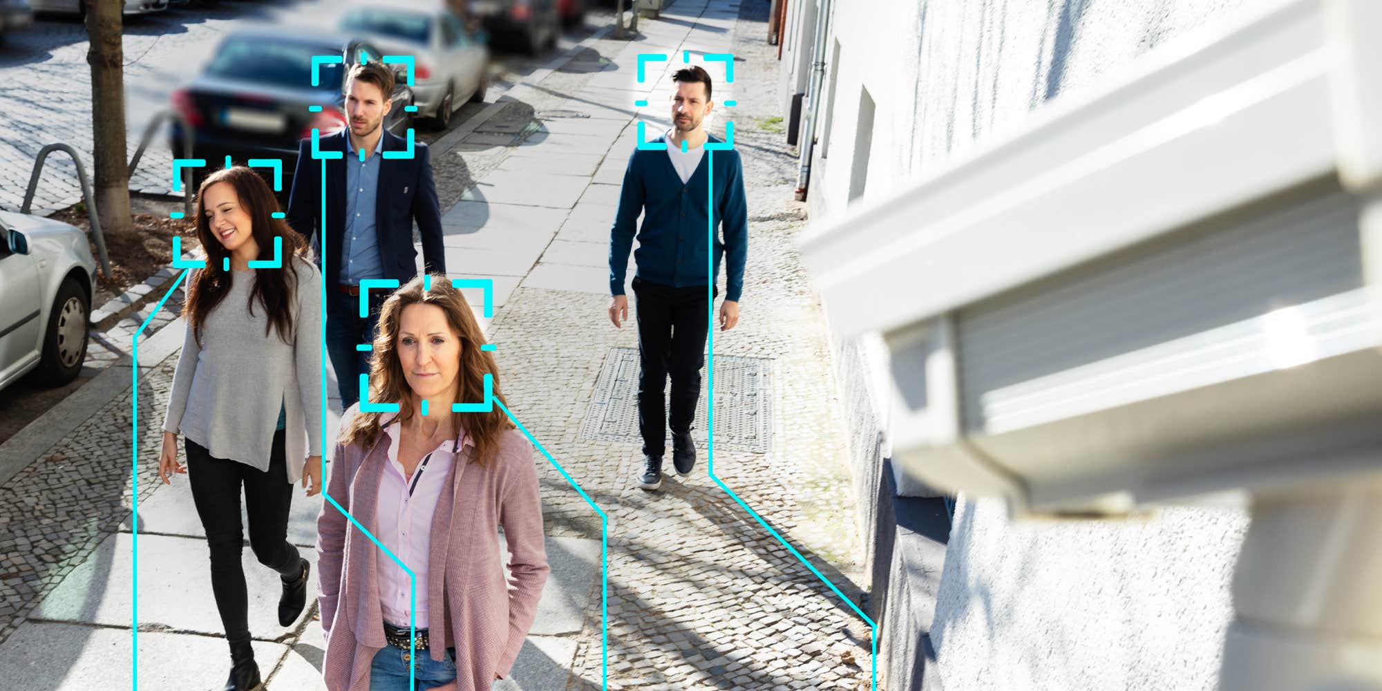 People walking on a sidewalk with a camera using facial recognition to scan them.