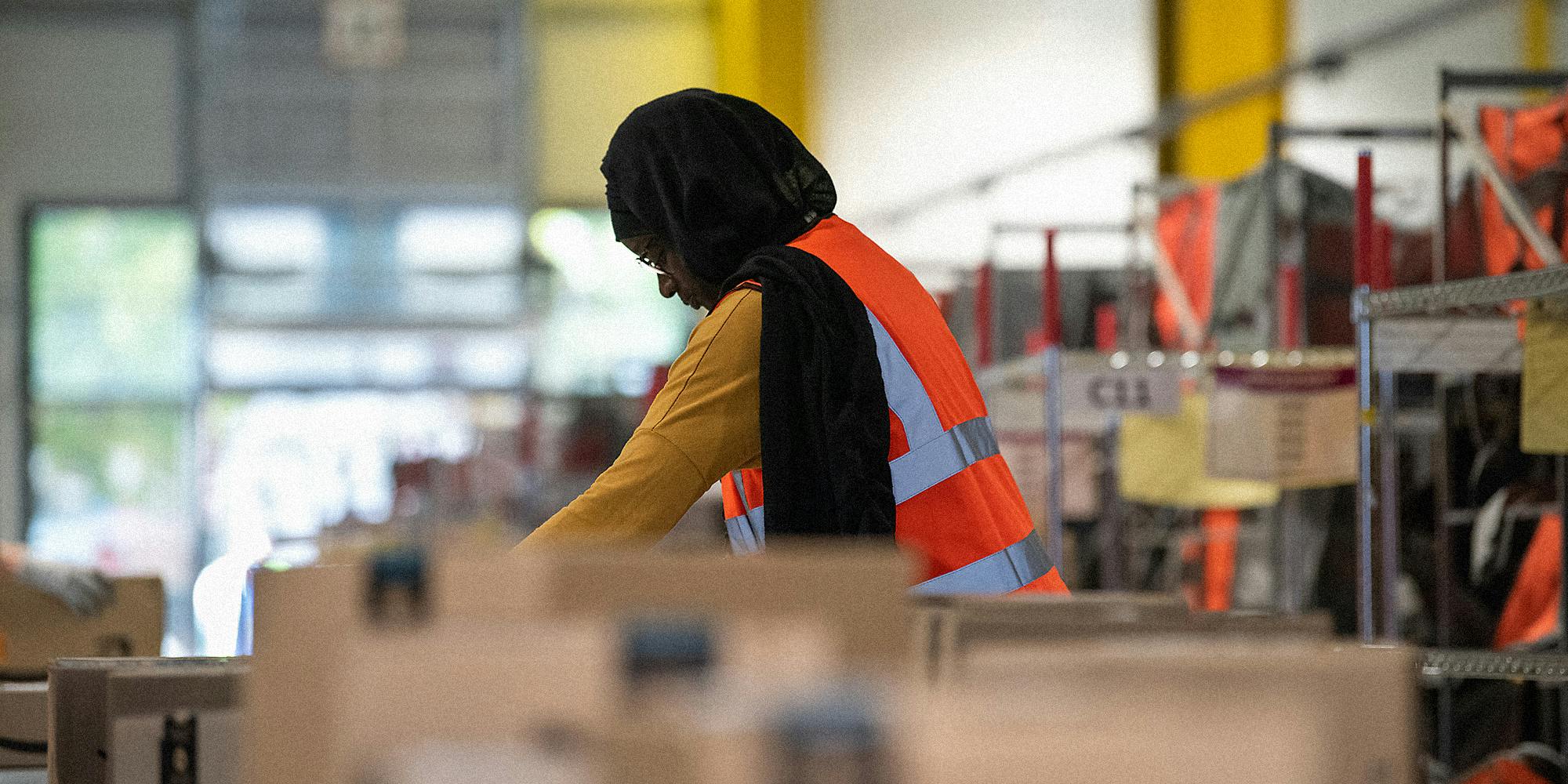 An Amazon employee inspects packages on an assembly line.