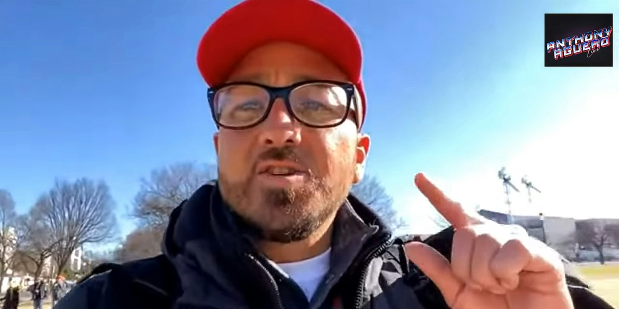 man in red hat and glasses pointing