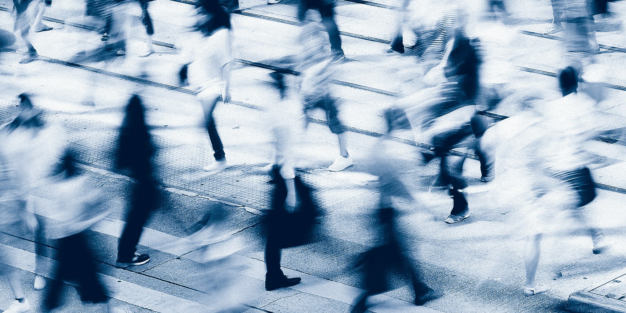 Motion blurred people walking in an intersection.