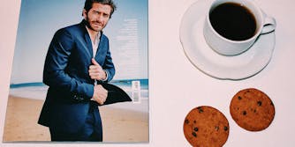 A magazine and cup of coffee with cookies.