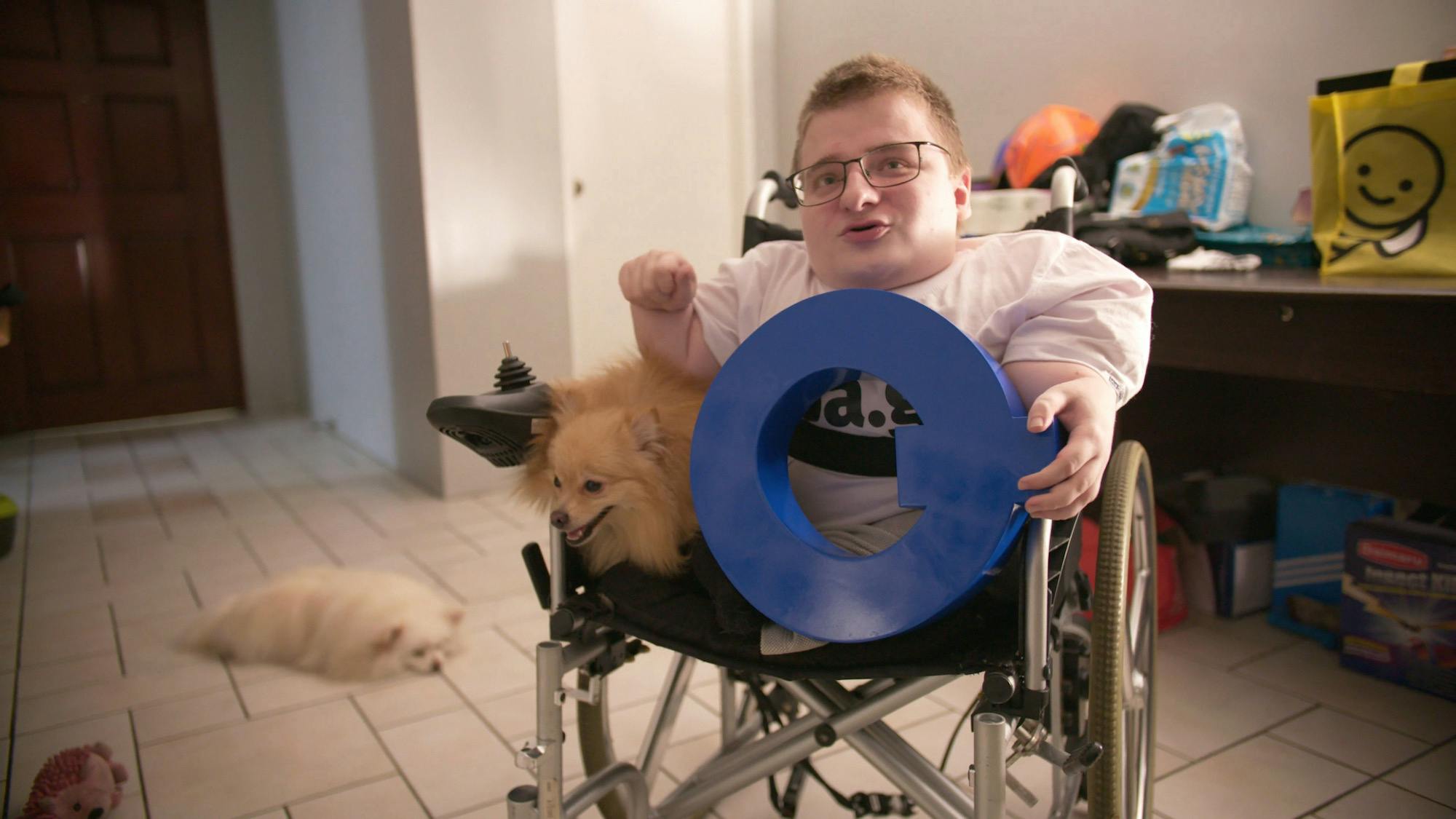 man in wheelchair holding letter q