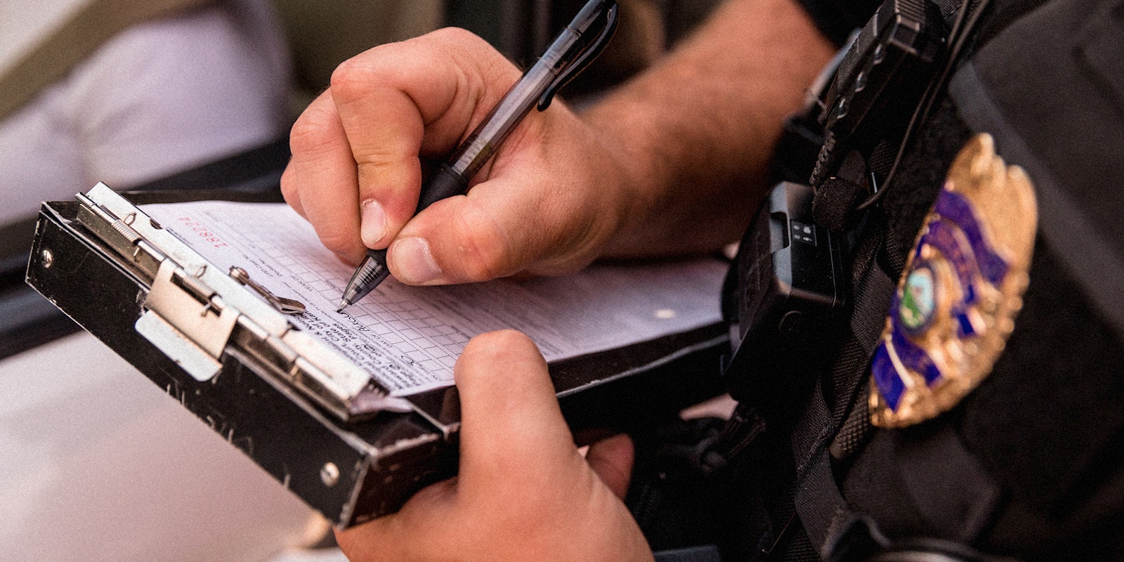 An officer's hands writing a ticket.