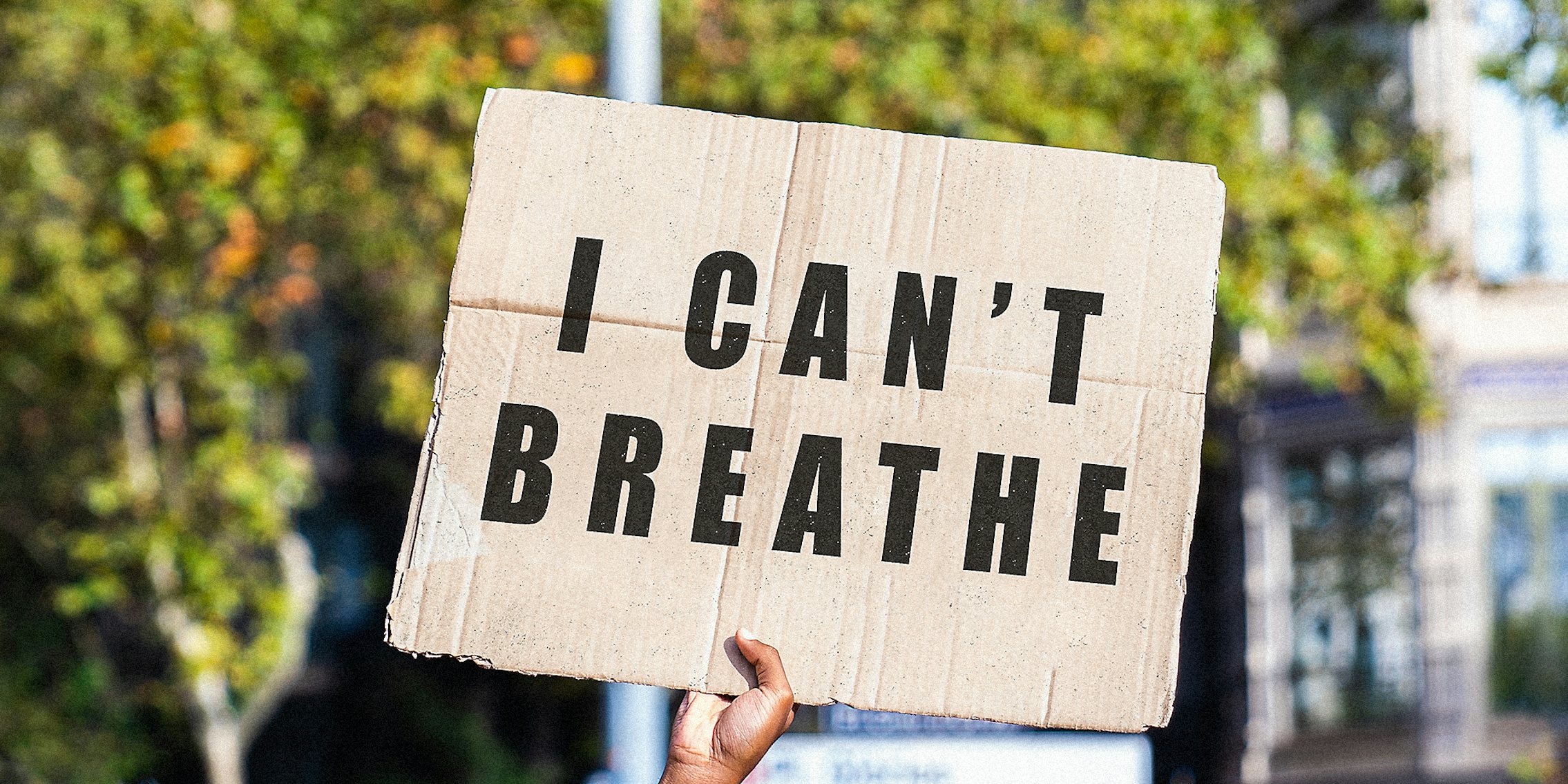 A hand holding a sign that read 'I Can't Breathe.'
