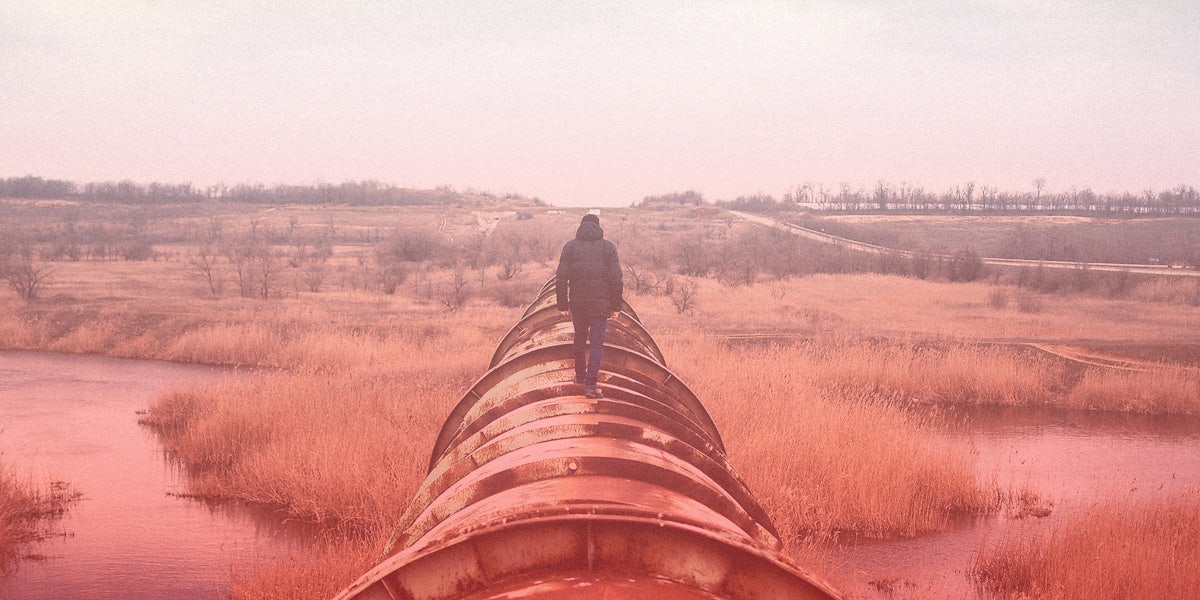 A man walks on an industrial pipeline.