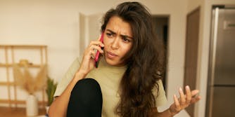 Frustrated young Hispanic woman being angry because of spam unwanted robocall.