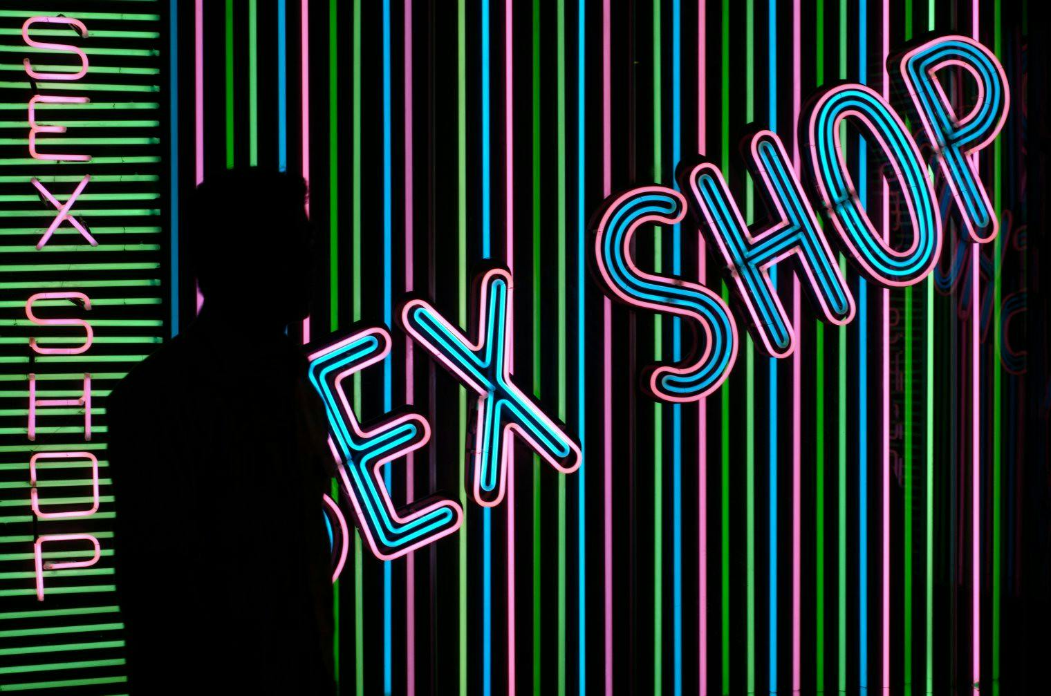 A silhouette stands next to a 'sex shop' sign