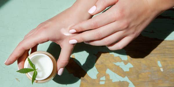 woman applies a cannabis salve CBD topical cream to her hand.
