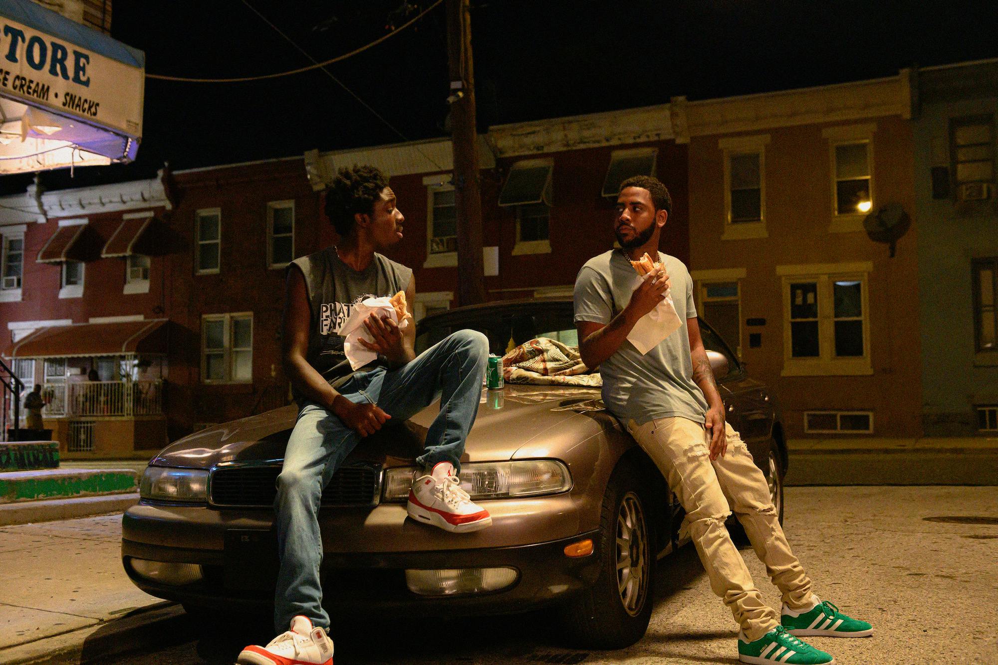 two teens sitting on the front of a car