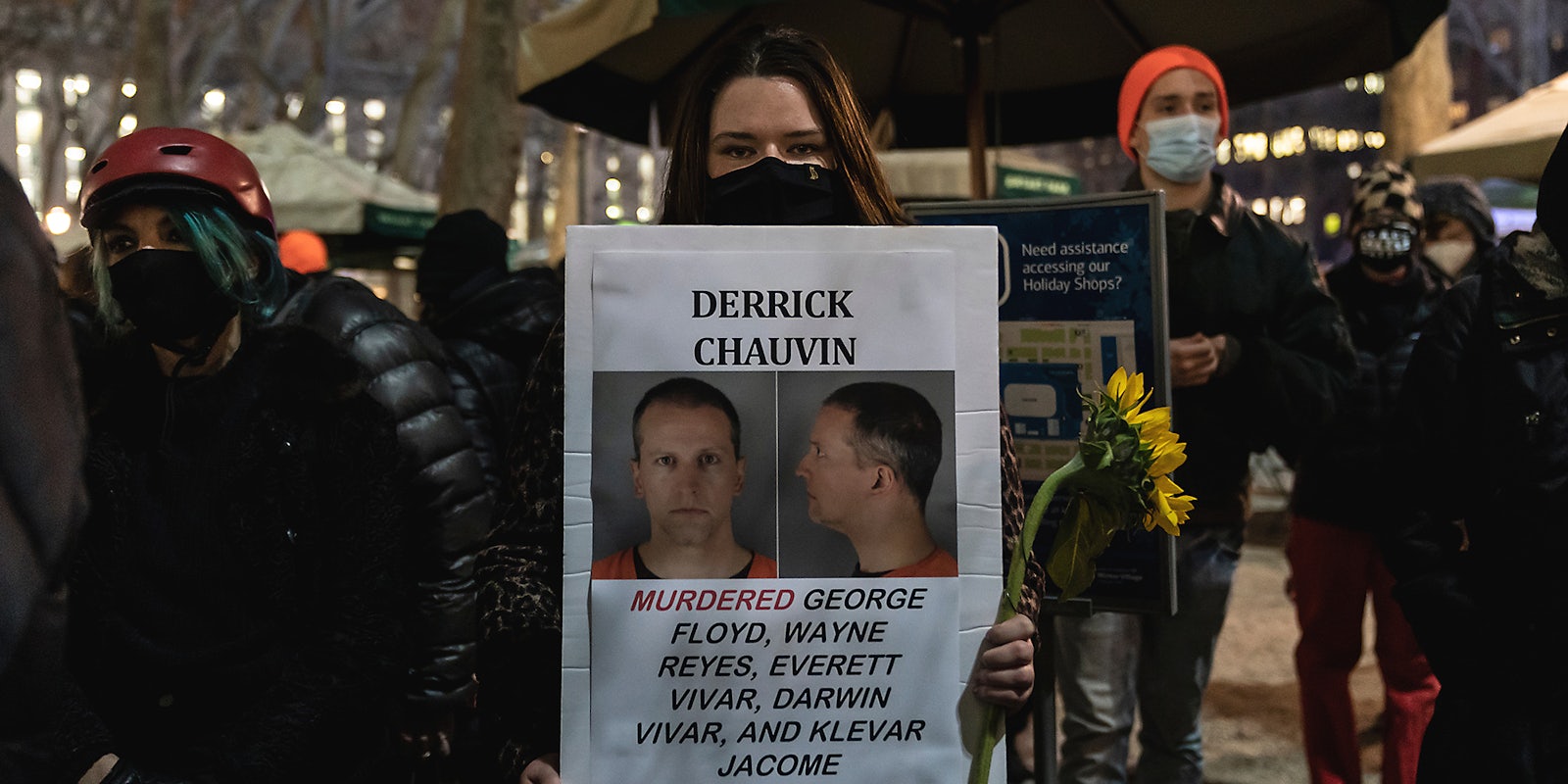 A woman holding a wanted sign for Derek Chauvin.