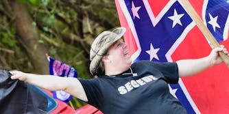 A woman shouting in front of a confederate flag.