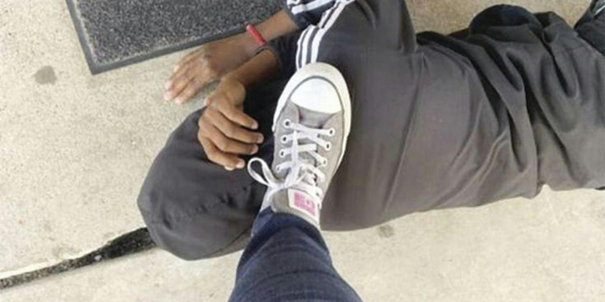 Someone's foot stepping on a black person's neck while they are lying on the ground