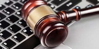 A gavel resting on a laptop's keyboard.