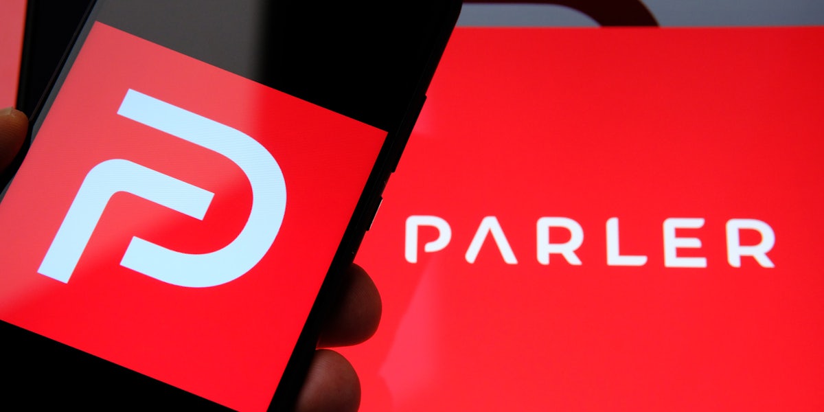 The Parler logo on a smartphone with the Parler name in the background.