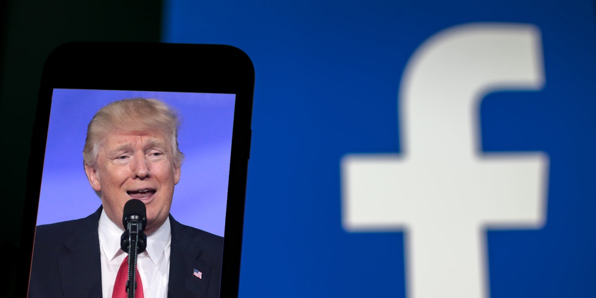 A photo of former President Donald Trump on a phone. In the background, the Facebook logo is blurred out.