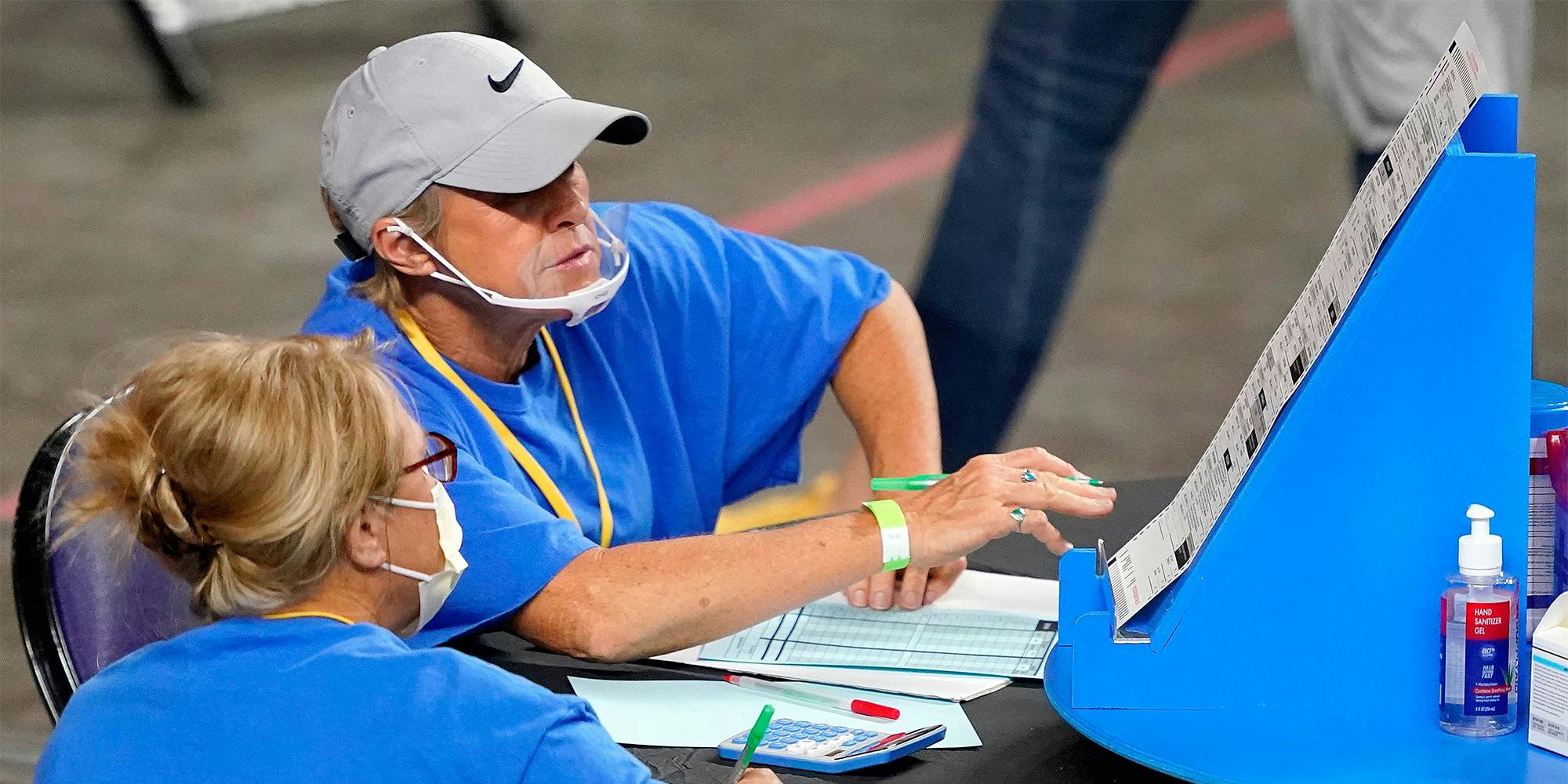 A man and woman examine election ballots.