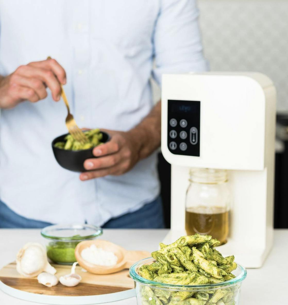 LEVO weed machine and cannabutter maker sits on a counter as someone prepares infused pesto pasta.