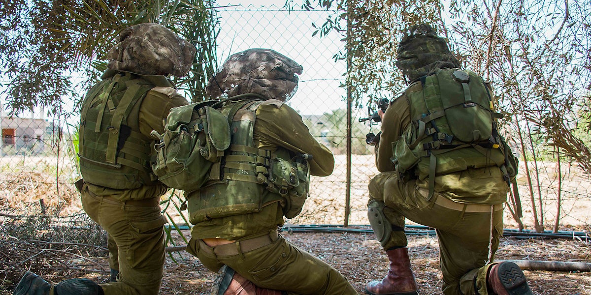 Three military members in a field.