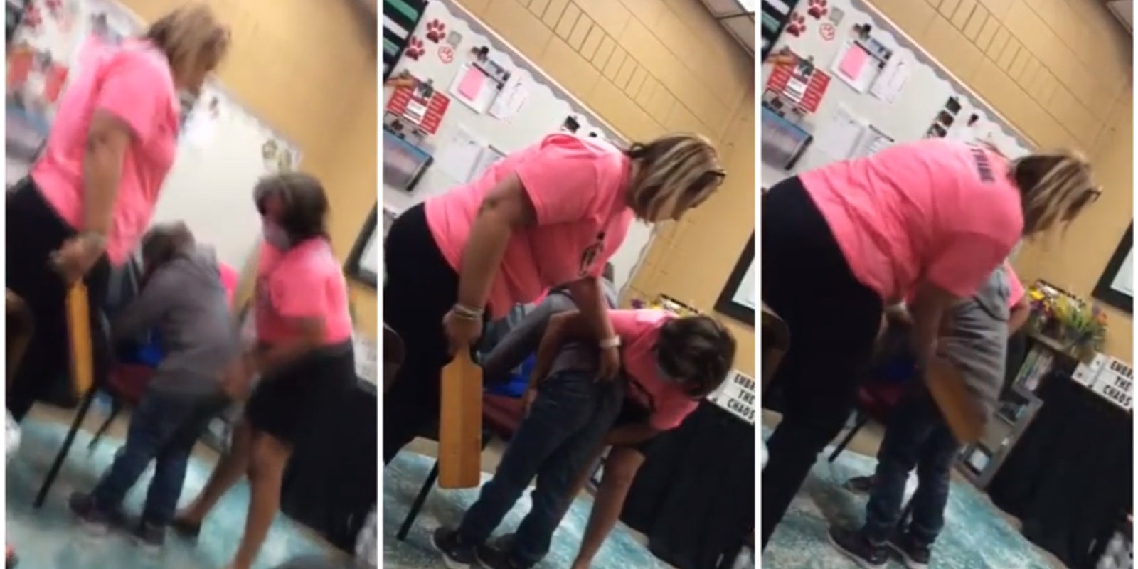 Two women in pink shirts restrain and assault a child with a wooden paddle.