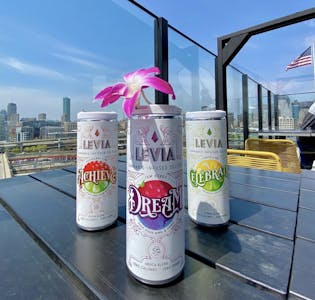 LEVIA cannabis-infused seltzer THC drinks sit on a table overlooking a city landscape.