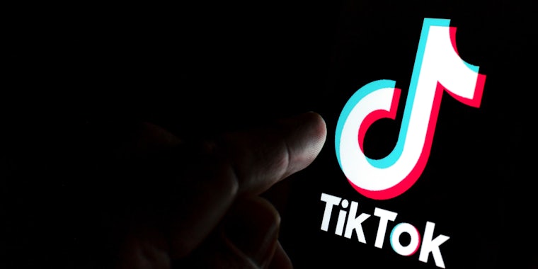 TikTok app logo on screen and a finger pointing at it.