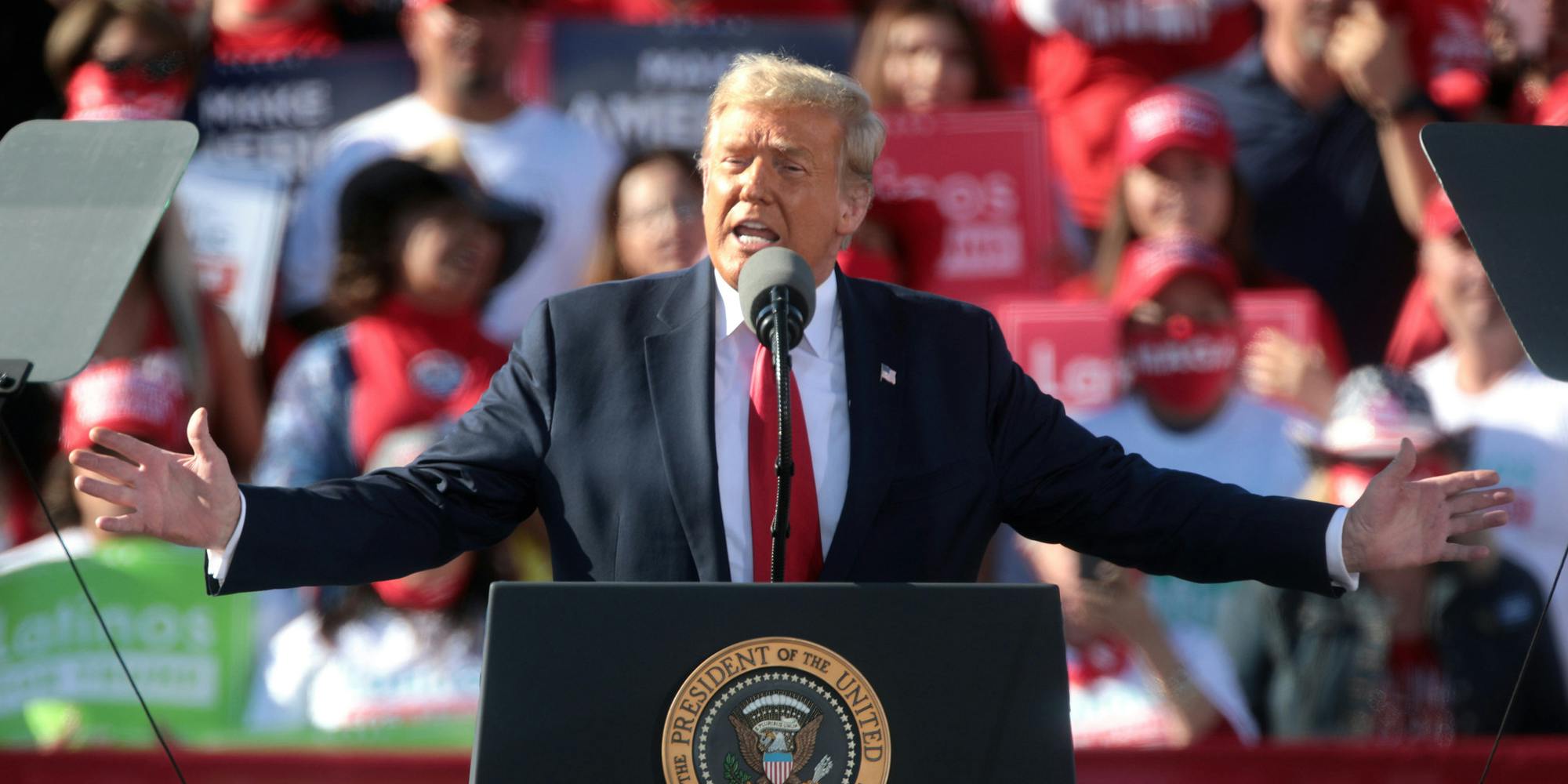 Former President Donald Trump speaking at a podium at a rally.