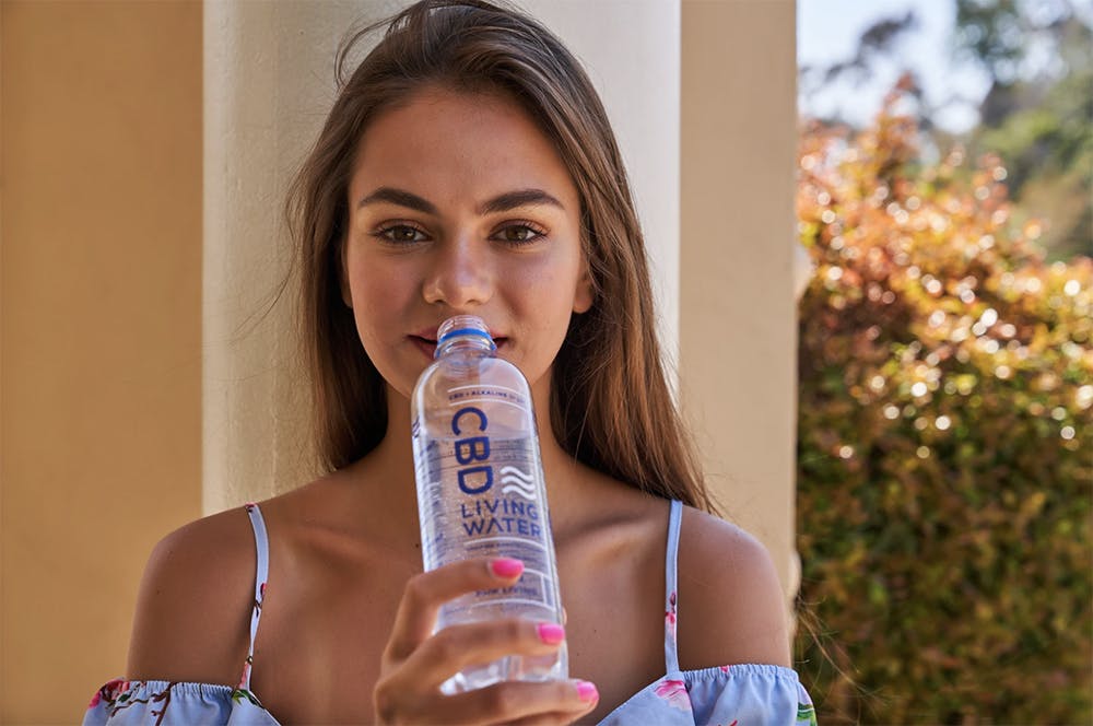 woman drinks CBD water outside
