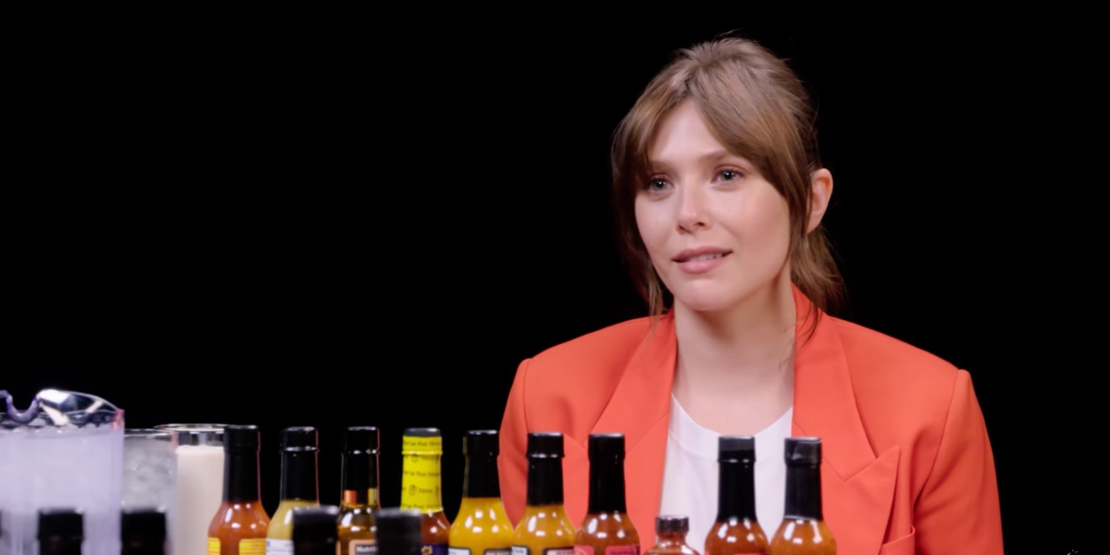 woman sitting in front of hot sauce bottles