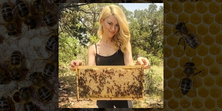 woman holds hive comb with bees