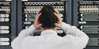 man in network server room with hands on head