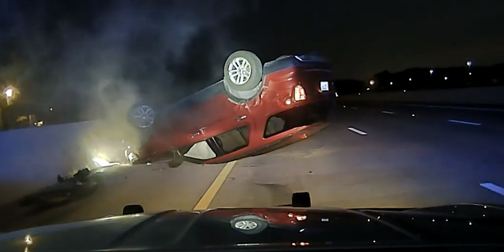 car crashed upside down on highway from perspective of a police cruiser