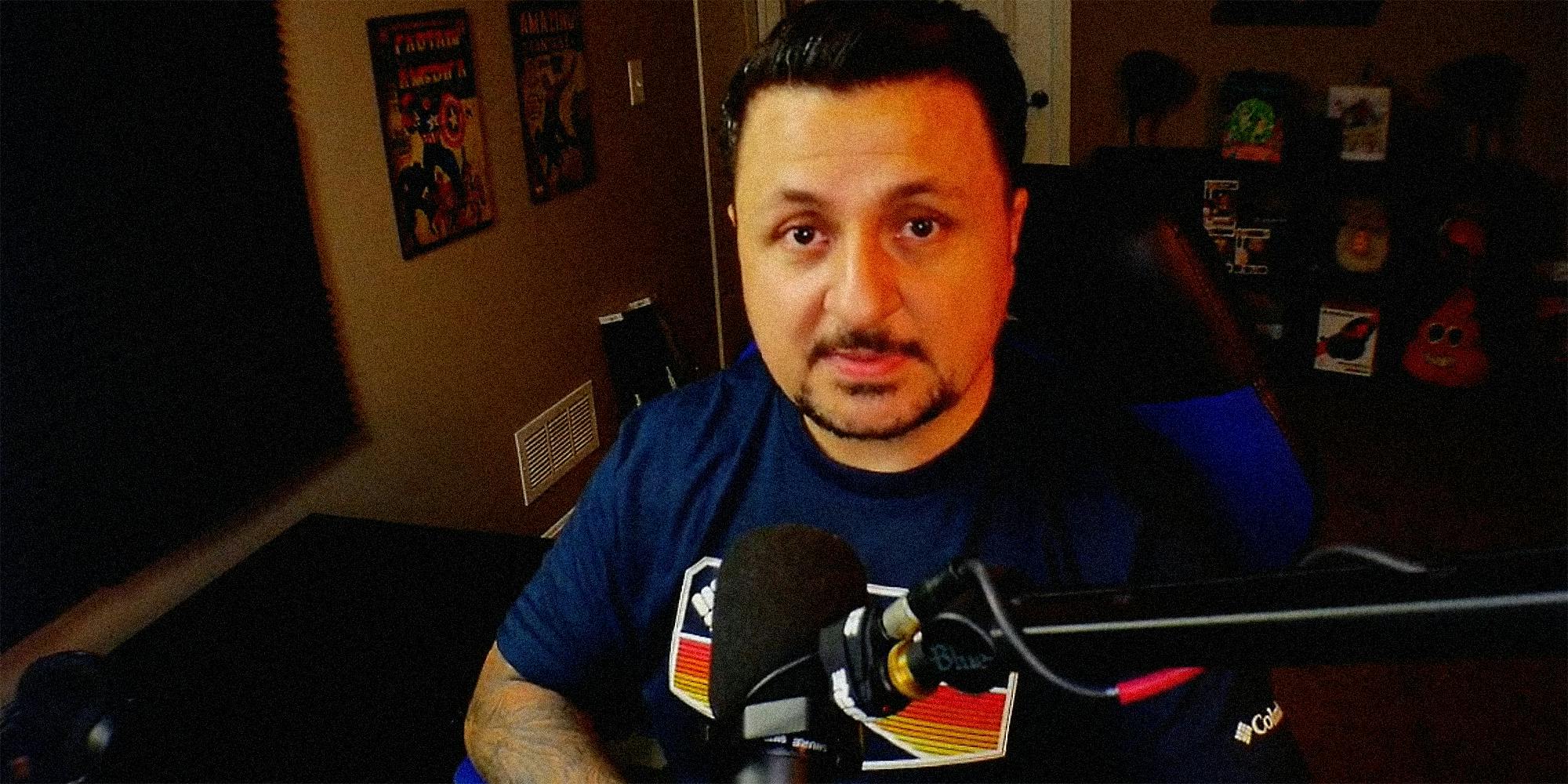 A man at a desk with microphone talking into camera.