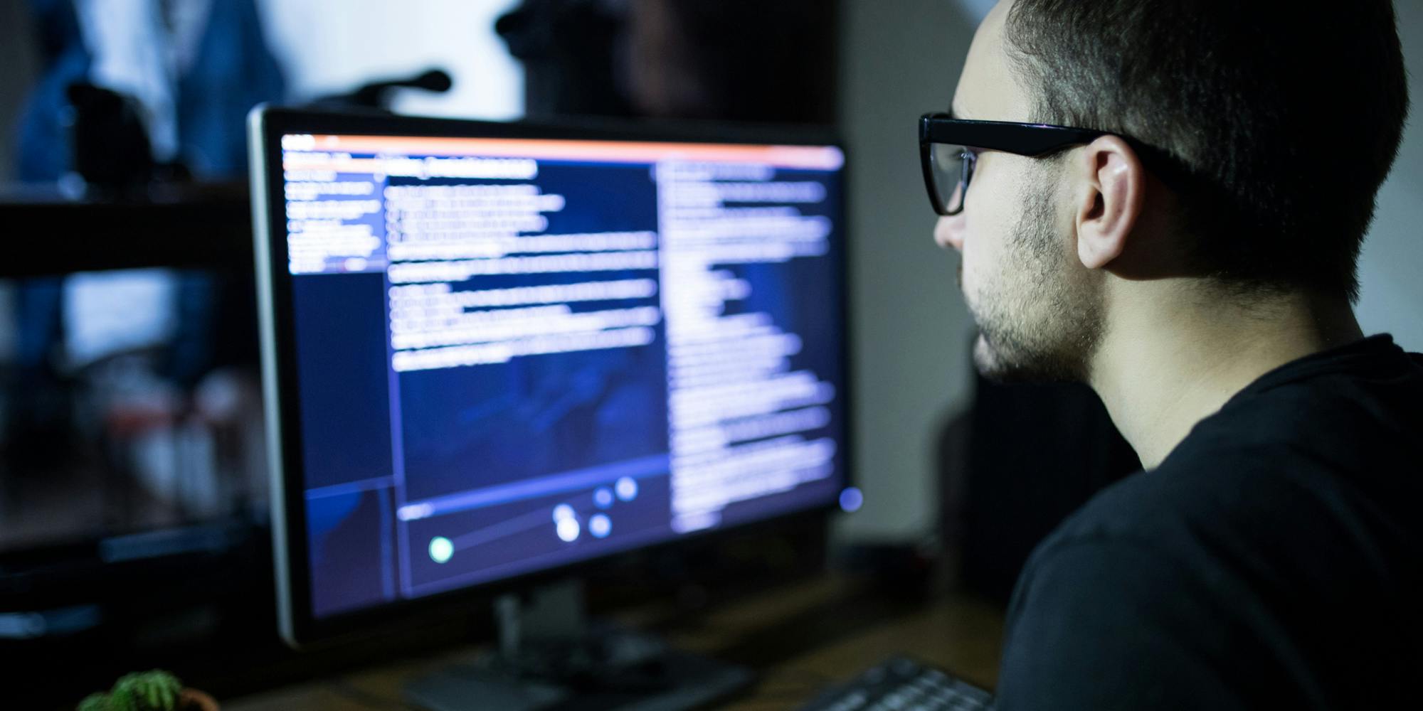 A person at a computer carrying out a cyber attack in the dark.