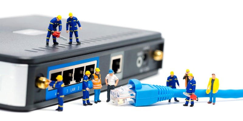 Figurines of broadband technicians putting an ethernet cord into a router. It is meant to convey rural broadband deployment.