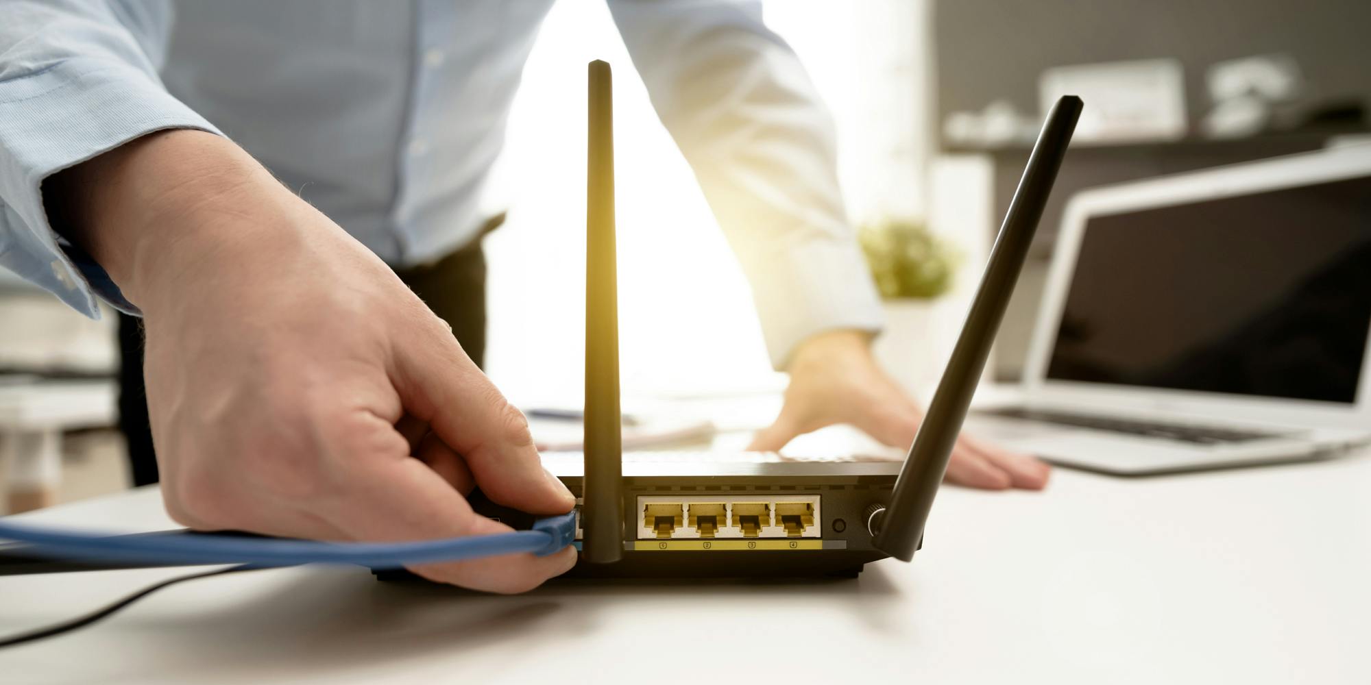 Man connects the internet cable to the router's socket. Fast and wireless broadband internet concept.